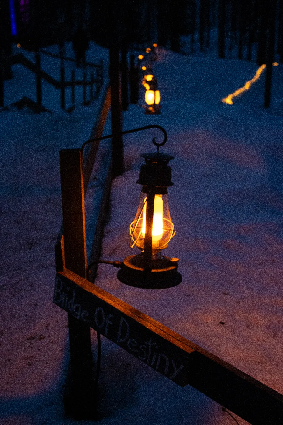 Beleuchteter, verschneiter Pfad im Arcandia Arctic Adventure Park mit einem Schild „Circle Of Destiny“ im Vordergrund.